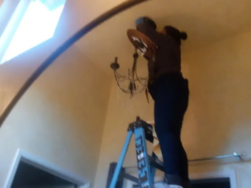 Electrician installing a chandelier in a Jackson residence